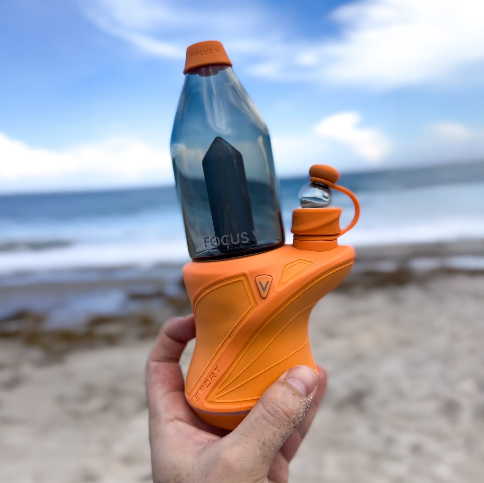 Lifestyle photography of a Focus V CARTA SPORT electric dab rig used at the beach outdoors, highlighting a portable electric rig setup designed for consistent sessions beyond a traditional dab station